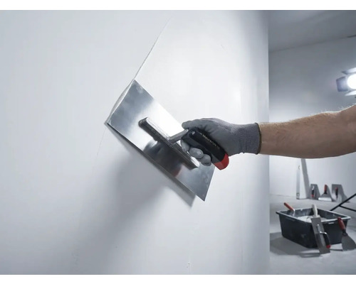 Ruka s hladítkem na sádru při hlazení stěny