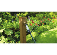 Zahradní scéna s vodovodním kohoutkem a zahradní hadicí na dřevěném sloupku