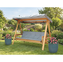 Dřevěná houpačka s šedými podložkami a stříškou na zahradě