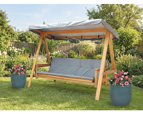 Dřevěná houpačka s šedými podložkami a stříškou na zahradě