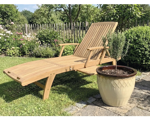 Dřevěné zahradní lehátko vedle květináče s rostlinou na zahradě