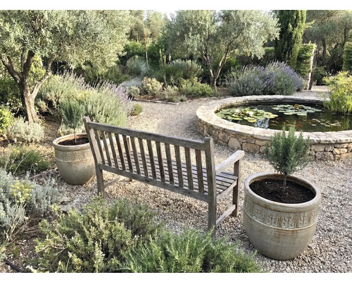 Zahradní scéna s dřevěnou lavicí, květináči a jezírkem