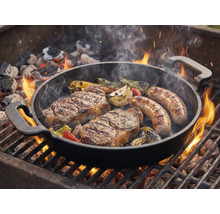 Grilovací pánev se steaky, klobásami a zeleninou na grilu