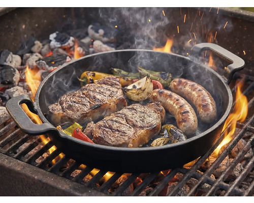 Grilovací pánev se steaky, klobásami a zeleninou na grilu