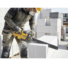 Stavební dělník řeže pórobetonovou tvárnici pilou na kámen DeWalt.