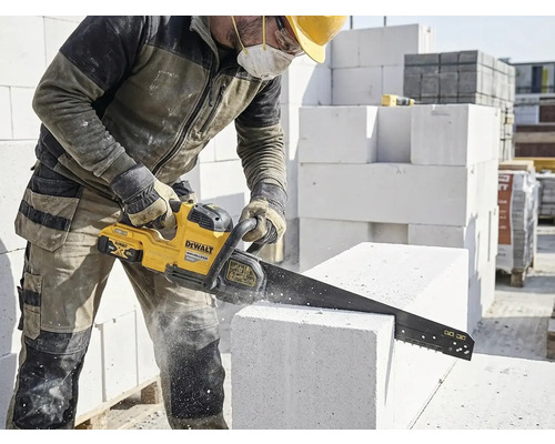 Stavební dělník řeže pórobetonovou tvárnici pilou na kámen DeWalt.
