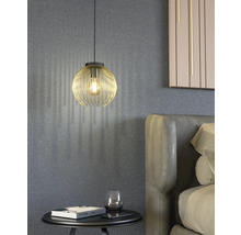 Scéna se zlatým závěsným svítidlem nad nočním stolkem vedle postele.