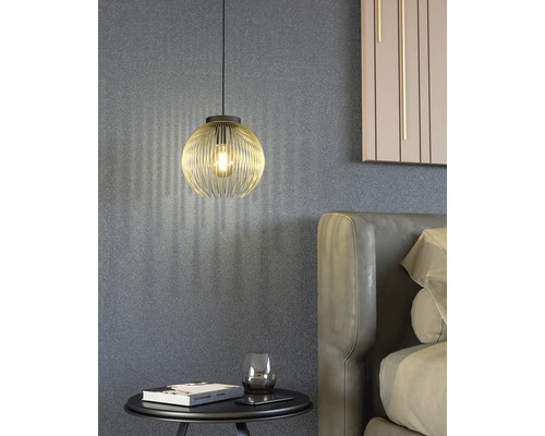 Scéna se zlatým závěsným svítidlem nad nočním stolkem vedle postele.