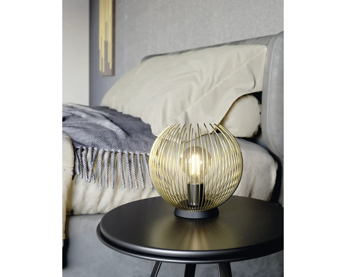 Zlatá drátěná kulová lampa na stole v ložnici