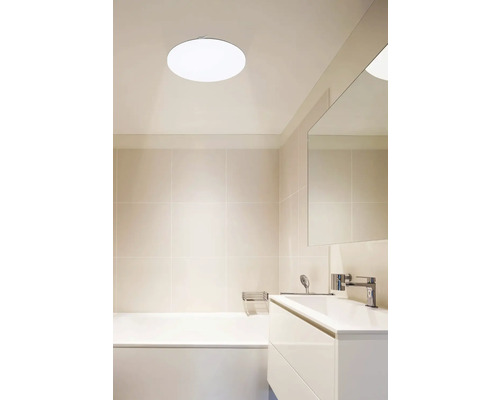 Světlá koupelna s vanou, umyvadlem a kulatým stropním svítidlem