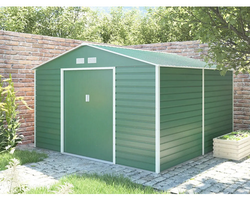 Kovový zahradní domek v zelené barvě se sedlovou střechou a posuvnými dveřmi, umístěný v zahradě na dlažbě před cihlovou zdí.