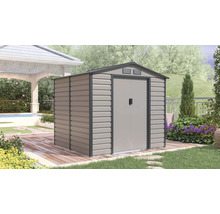 Kovový zahradní domek se sedlovou střechou a dvoukřídlými dveřmi na dřevěné terase ve světlé, uspořádané zahradě.