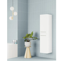 Vysoká, bílá závěsná koupelnová skříňka se dvěma úchyty v moderní koupelně se světle modrými obklady a pokojovou rostlinou.