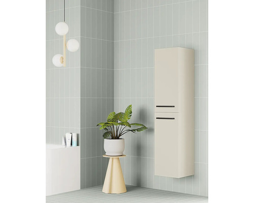 Moderní béžová nástěnná koupelnová skříňka s černými úchyty ve světle zeleně obložené koupelně s pokojovou rostlinou a kulatým svítidlem.