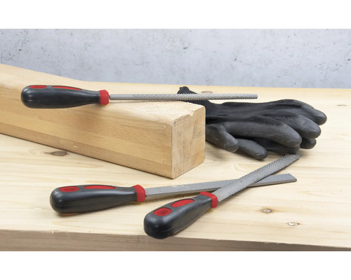 Dřevěný blok, rukavice a různé pilníky na dřevěném povrchu.