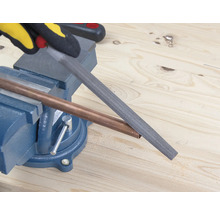 Měděná trubka opracovávaná pilníkem, který je upevněn ve svěráku.