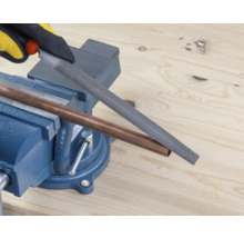 Měděná trubka je opracovávána pilníkem upnutým ve svěráku.