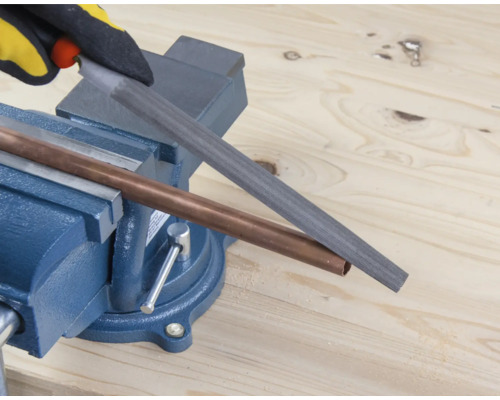 Měděná trubka je opracovávána pilníkem upnutým ve svěráku.