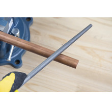 Měděná trubka ve svěráku s kovovým pilníkem