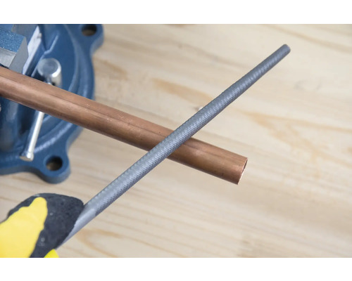 Měděná trubka ve svěráku s kovovým pilníkem