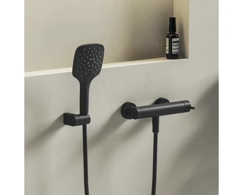 Sprchový set v matně černé barvě s hranatou ruční sprchou a válcovou termostatickou baterií pro montáž na stěnu.
