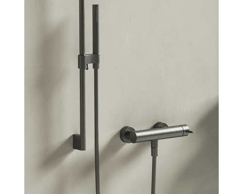 Moderní sprchový systém s ruční sprchou, sprchovou tyčí a termostatickou baterií z kartáčovaného tmavého kovu.
