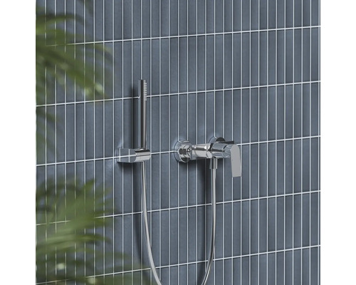 Chromová páková vanová baterie s tyčovou ruční sprchou na moderně obložené stěně.