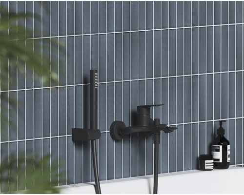 Černá nástěnná vanová baterie s ruční sprchou na vertikálně obložené stěně v moderní koupelně.