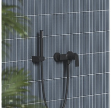 Černá nástěnná vanová baterie s ruční sprchou a držákem na stěně s vertikálními obklady.