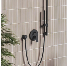 Černá podomítková sprchová baterie s ruční sprchou na dlážděné stěně v moderní koupelně.