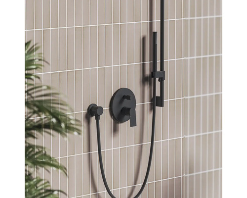 Černá podomítková sprchová baterie s ruční sprchou na dlážděné stěně v moderní koupelně.