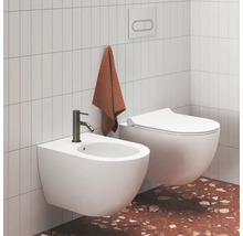 Světlá moderní koupelna se závěsným bidetem s tmavou baterií a závěsným WC u obložených stěn a terazzové podlahy.