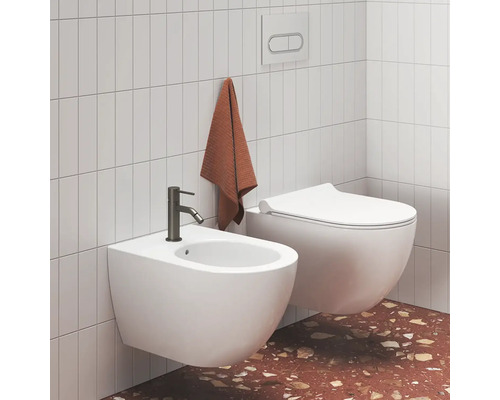 Světlá moderní koupelna se závěsným bidetem s tmavou baterií a závěsným WC u obložených stěn a terazzové podlahy.