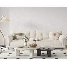 Moderní obývací pokoj s bílou strukturovanou tapetou, velkou pohovkou, kulatými stolky a stojací lampou na vzorovaném koberci.