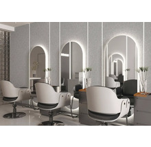 Moderní kadeřnictví se třemi osvětlenými obloukovými zrcadly na strukturované stěně, bílými otočnými křesly a šedými odkládacími stolky.