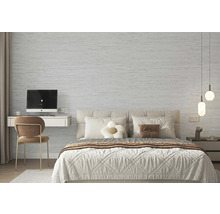 Moderní ložnice se světle šedou strukturovanou stěnou s kamenným vzhledem, manželskou postelí a malým pracovním koutem.