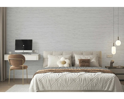 Moderní ložnice se světle šedou strukturovanou stěnou s kamenným vzhledem, manželskou postelí a malým pracovním koutem.