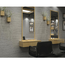 Moderní kadeřnictví s obdélníkovými zrcadly v dřevěných rámech, nástěnnými konzolami a černými křesly před strukturovanou stěnou.