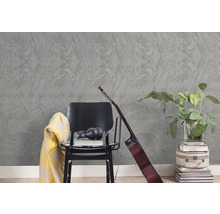 Strukturovaná šedá tapeta s hvězdicovým vzorem v moderním interiéru s černou židlí, kytarou a pokojovou rostlinou.