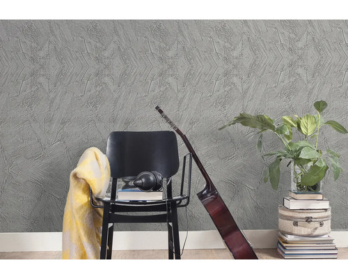 Strukturovaná šedá tapeta s hvězdicovým vzorem v moderním interiéru s černou židlí, kytarou a pokojovou rostlinou.