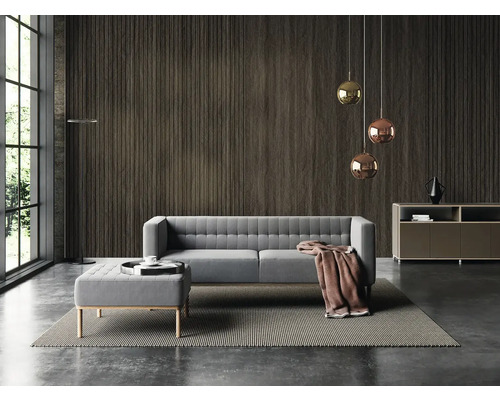 Moderní obývací pokoj s tmavým nástěnným panelem ve vzhledu dřeva, šedou polstrovanou pohovkou s taburetem, závěsnými svítidly a velkým oknem.