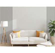 Moderní obývací pokoj s bílou pohovkou, žlutými polštáři, dřevěnou stojací lampou a nástěnnou dekorací s černými svislými pruhy.