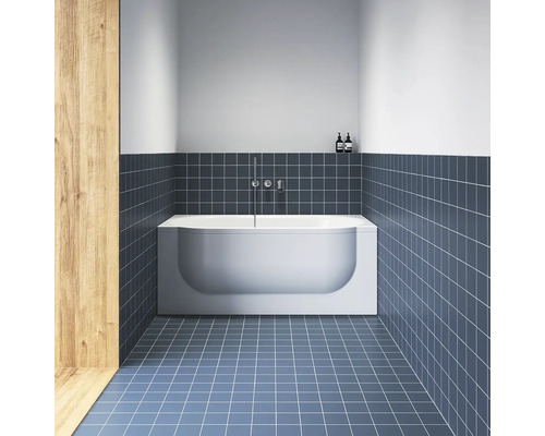 Moderní koupelna s bílou obdélníkovou vanou, modrými čtvercovými dlaždicemi na podlaze i stěnách a chromovanou nástěnnou baterií.