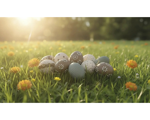 Dekorativní velikonoční vajíčka s různými vzory jako květiny a tečky leží na prosluněné louce s trávou a květinami.