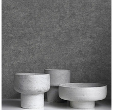 Tři moderní květináče v betonovém vzhledu s podstavcem před strukturovanou stěnou.