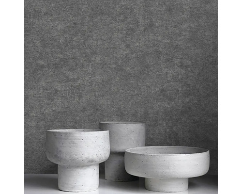 Tři moderní květináče v betonovém vzhledu s podstavcem před strukturovanou stěnou.