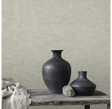 Vliesová tapeta ve vzhledu kamene se strukturovaným povrchem před rustikální dekorací s černými vázami a dřevěnou lavicí.