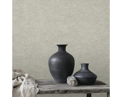 Vliesová tapeta ve vzhledu kamene se strukturovaným povrchem před rustikální dekorací s černými vázami a dřevěnou lavicí.