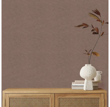 Jednobarevná hnědá tapeta s jemnou texturou v minimalistickém pokoji s dřevěnou komodou s ratanovými dvířky a bílou vázou.