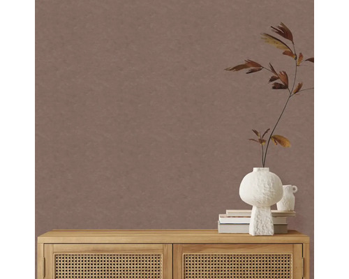 Jednobarevná hnědá tapeta s jemnou texturou v minimalistickém pokoji s dřevěnou komodou s ratanovými dvířky a bílou vázou.